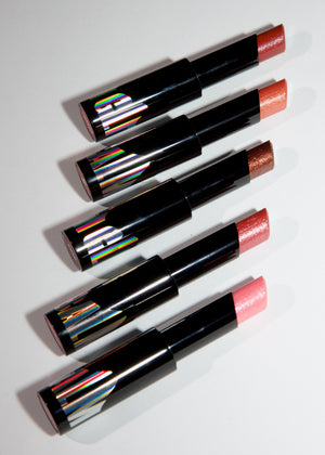 Five lipsticks in black tubes arranged diagonally on a white background, showing different lipstick shades including pink, orange, and brown, with holographic caps.